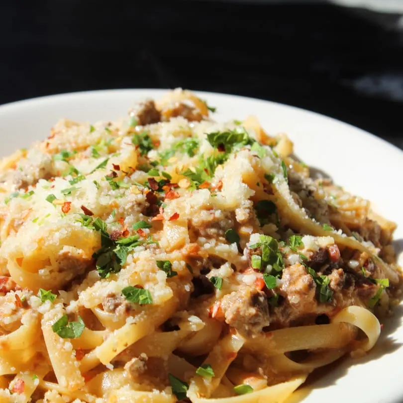 Close-up of Rig A' Tony's Italian pasta with meat sauce, parmesan, and parsley in a white bowl.