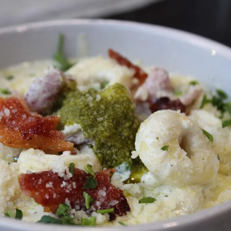 Rig A' Tony's Italian pasta dish with pesto, crispy prosciutto, and grated cheese.